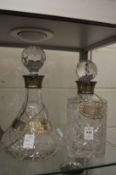 Two silver topped decanters and three silver decanter labels.