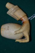 A carved meerschaum pipe modelled as a well carved hand holding the bowl.