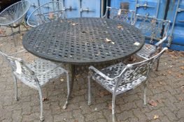 An aluminium circular garden table and five armchairs.