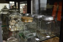 Glass storage jars, one containing a collection of seashells.