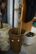 Copper twin handled bucket containing walking sticks and a crumb scoop and tray.