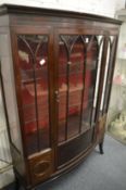 A mahogany bow fronted single door display cabinet.