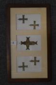 A group of bronze crosses, framed.