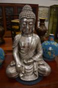 A silvered composite model of a seated Buddha.