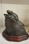 Patinated brass model of a frog on a rock.