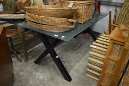 A large rectangular glass dining table on X shaped supports.