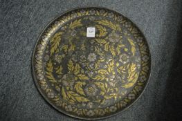 A cast metal circular dish inlaid with brass and silver coloured metal.