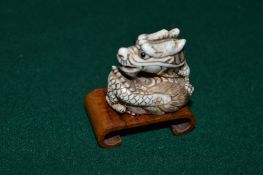 A Chinese carved bone dragon netsuke with stand.