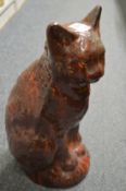 An Ewenny treacle glazed pottery model of a seated cat (restored).