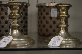 A pair of silver candlesticks with filled bases.