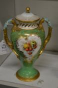 A Royal Worcester porcelain twin handled vase, green ground painted with a panel depicting fruit.