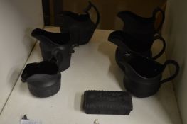 A collection of black basalt china jugs and a pin box and cover.