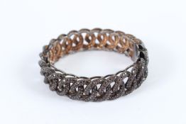 A DIAMANTE PIERCED INTERLACED BANGLE. 7cms.