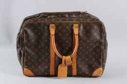A LARGE LOUIS VUITTON BRIEFCASE AND CLOTHES BAG with plain leather handles. 50cms long. Sold with