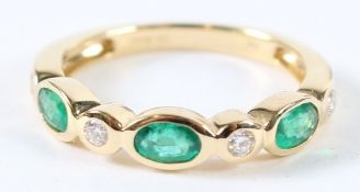 AN 18CT GOLD EMERALD AND DIAMOND HALF HOOP RING. Size O.