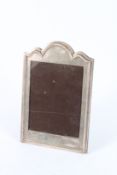 A SILVER PHOTOGRAPH FRAME with serpentine top. 20cms x 15cms.