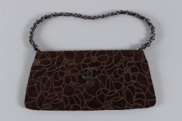A CHANEL DARK TAN FLOWER PATTERN PURSE with gilt and leather strap. 23cms long, with dust cover.