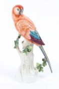 A CAPODIMONTE PORCELAIN PARROT on a tree stump. 32cms high.