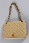 A CHANEL PADDED TAN LEATHER BAG with gilt double C and a gilt and leather strap. 23cms high, with