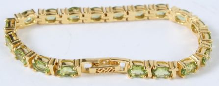 A SILVER AND 18CT GOLD PLATED PERIDOT TENNIS BRACELET.