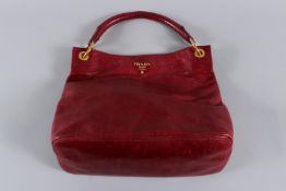 A PRADA RED SOFT LEATHER BAG with circular gilt badge and plain handle. 40cms long, with dust cover.