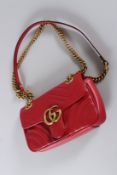 A SMALL RED LEATHER GUCCI PADDED BAG with leather strap and long gilt chain. No. 446744 498879.