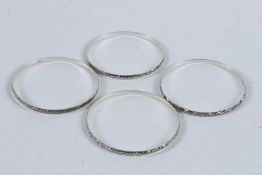 A SET OF FOUR STERLING SILVER BANGLES.