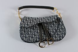 A CHRISTIAN DIOR SADDLE BAG OR BELT BAG, 30cms long, with dust cover. Christian Dior Card 44 88 4