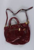 A LARGE PRADA SOFT DEEP RED LEATHER BAG with small handle and long strap. 40cms long. Sold with