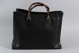 A VINTAGE GUCCI BLACK LEATHER BAG with bamboo handles. 43cms long. Sold with Authentication