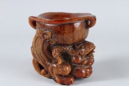 A GOOD CHINESE CARVED HORN LIBATION CUP, carved with dragons. 11cms high