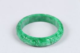 A CARVED JADE BANGLE. 3ins diameter