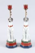 A PAIR OF SEVRES DESIGN PORCELAIN DOG CANDLESTICKS on hexagonal bases. 14ins high