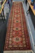 A Persian design runner, red ground with geometric decoration, 400cm x 85cm.