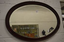 A mahogany oval wall mirror.