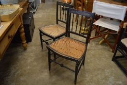 A pair of decoratively painted cane work seated occasional chairs.