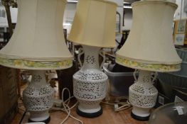 A set of three white porcelain reticulated table lamps.