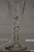 An 18th century wine glass with engraved bowl and facet cut stem.