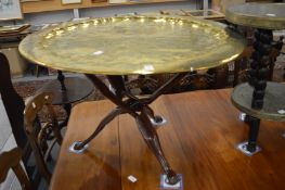 A large Eastern brass circular tray with engraved decoration on associated folding base.