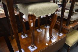 An upholstered stool on cabriole legs.