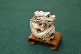 A bone netsuke with wooden stand.