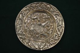 An Eastern white metal circular dish embossed with animals and birds.