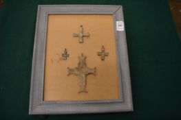 Four bronze crucifixes on framed mount.