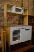 A childs toy kitchen unit and a small table and chair.