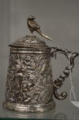 An Eastern white metal lidded tankard with embossed and chased decoration.