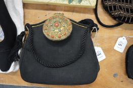 A black fabric evening bag, the decorative clasp combined with a small mirror.