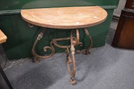 Decorative demi lune table with painted wooden top on an ornate wrought iron base.