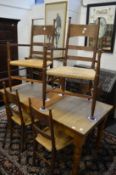 In the manner of William Birch, a set of six oak and rush seated Arts and Crafts dining chairs,