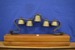 A set of five bells mounted on a wooden plinth.