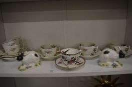 Decorative cups and saucers and a pair of pottery rabbits.